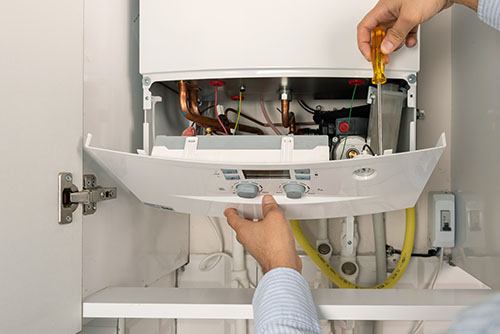 Heating technician repairing a residential boiler in Costa Mesa