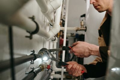 Technician inspecting commercial plumbing pipes in Costa Mesa
