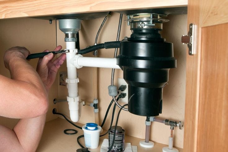Plumber repairing a garbage disposal in Costa Mesa
