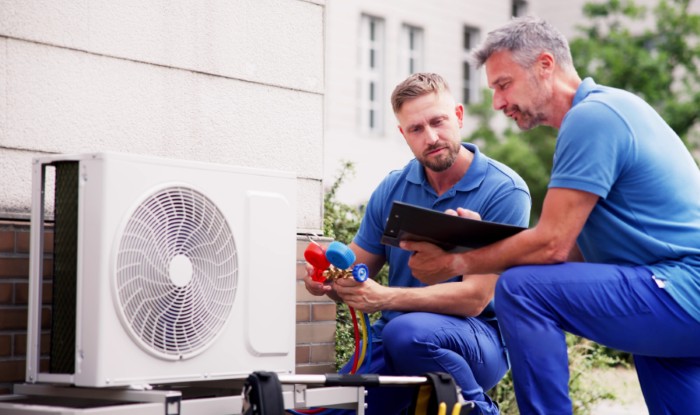 HVAC technicians installing an outdoor air conditioning unit in Costa Mesa