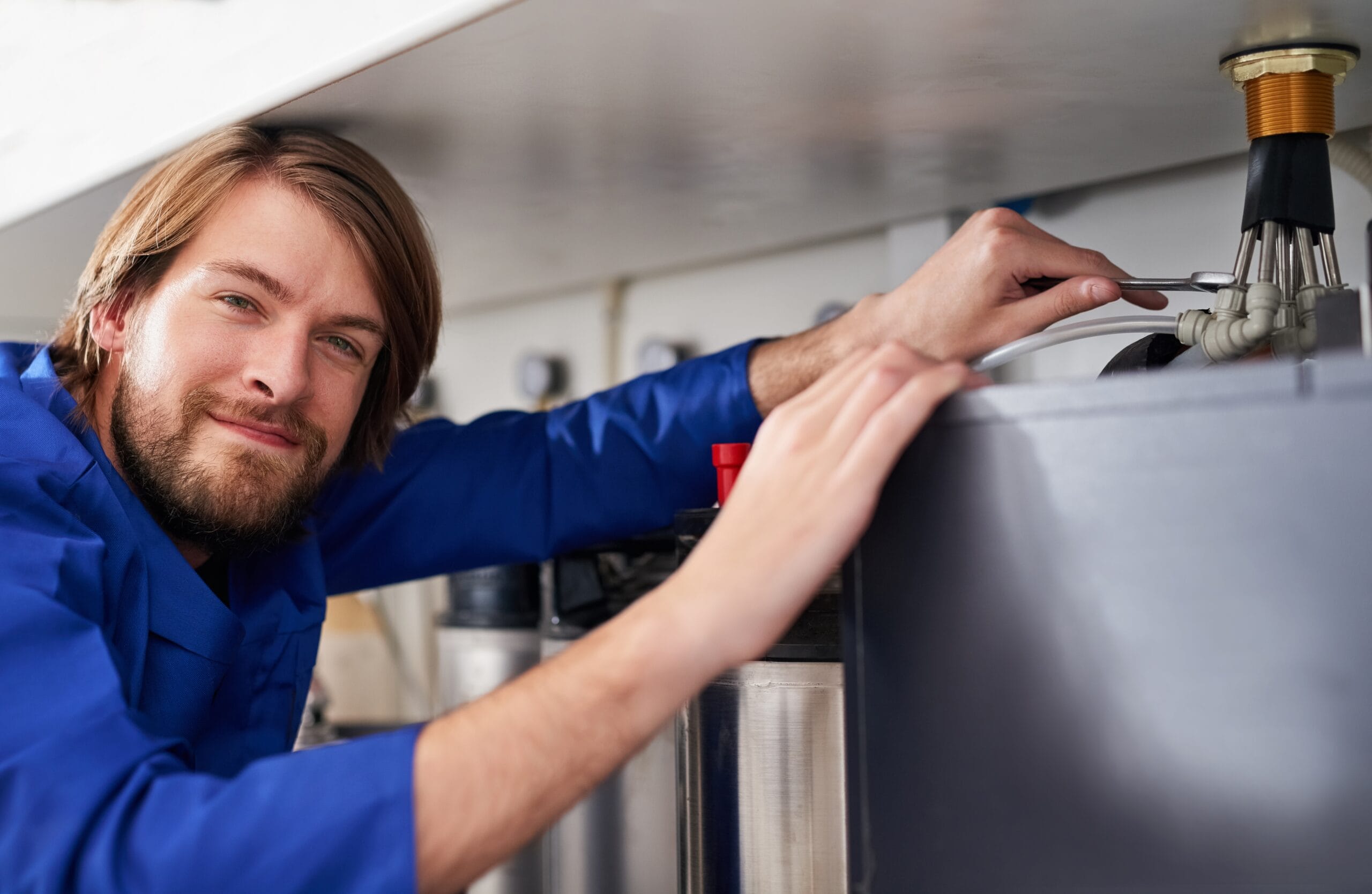Technician servicing a residential water heater tank in Costa Mesa